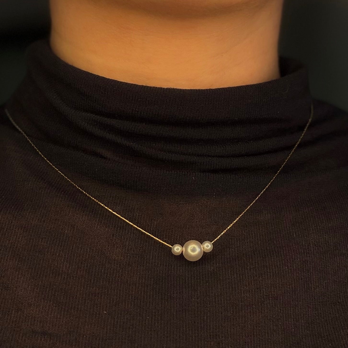 Pearl necklace on a person wearing a black turtleneck