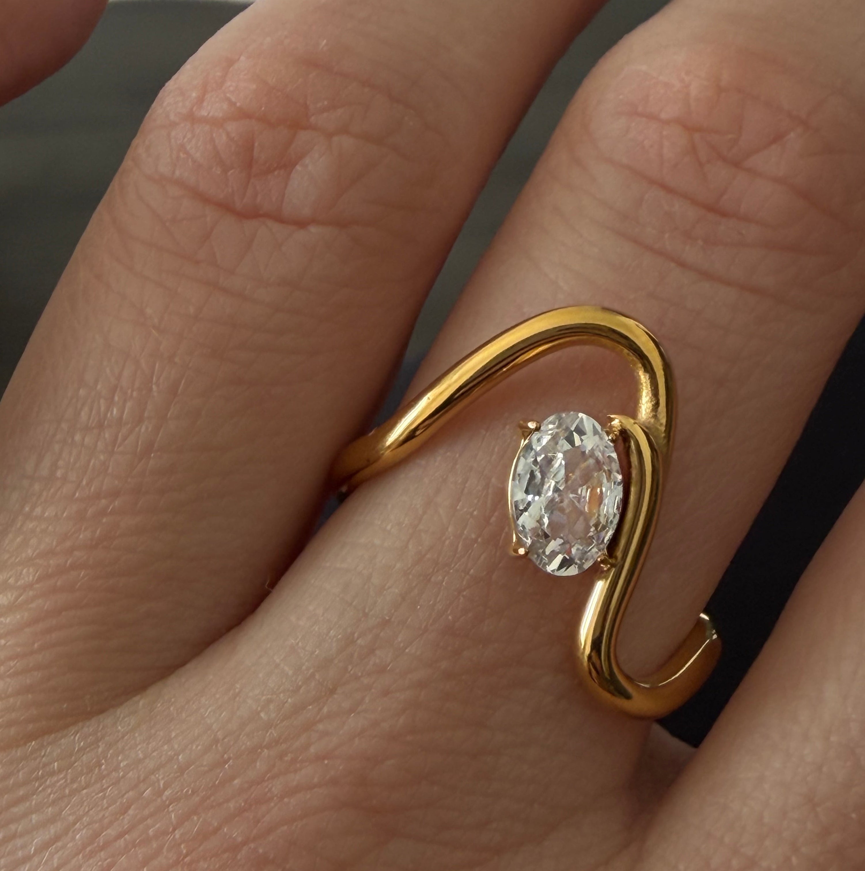 Gold ring with a zircon on a finger