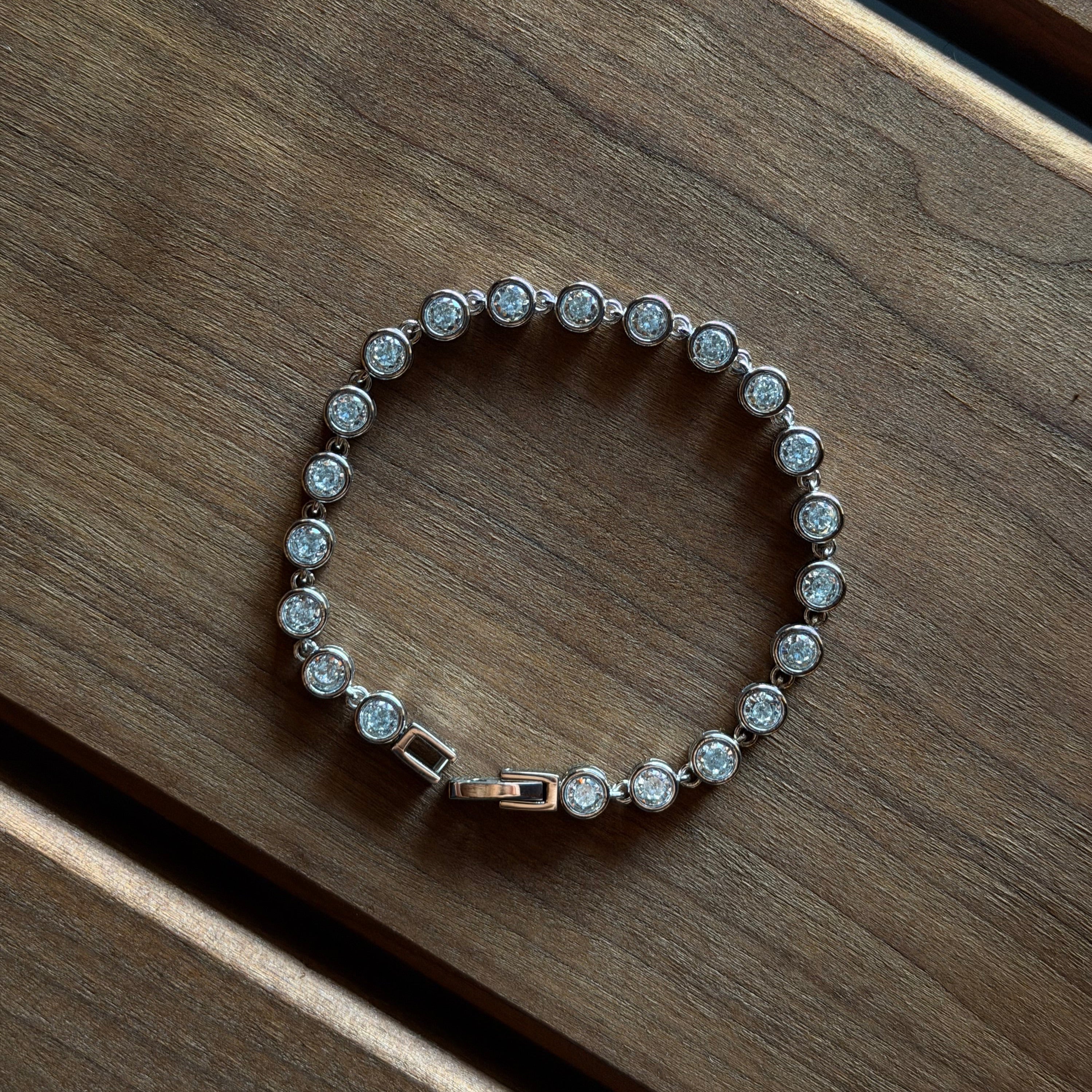 Silver bracelet with clear stones on a wooden surface